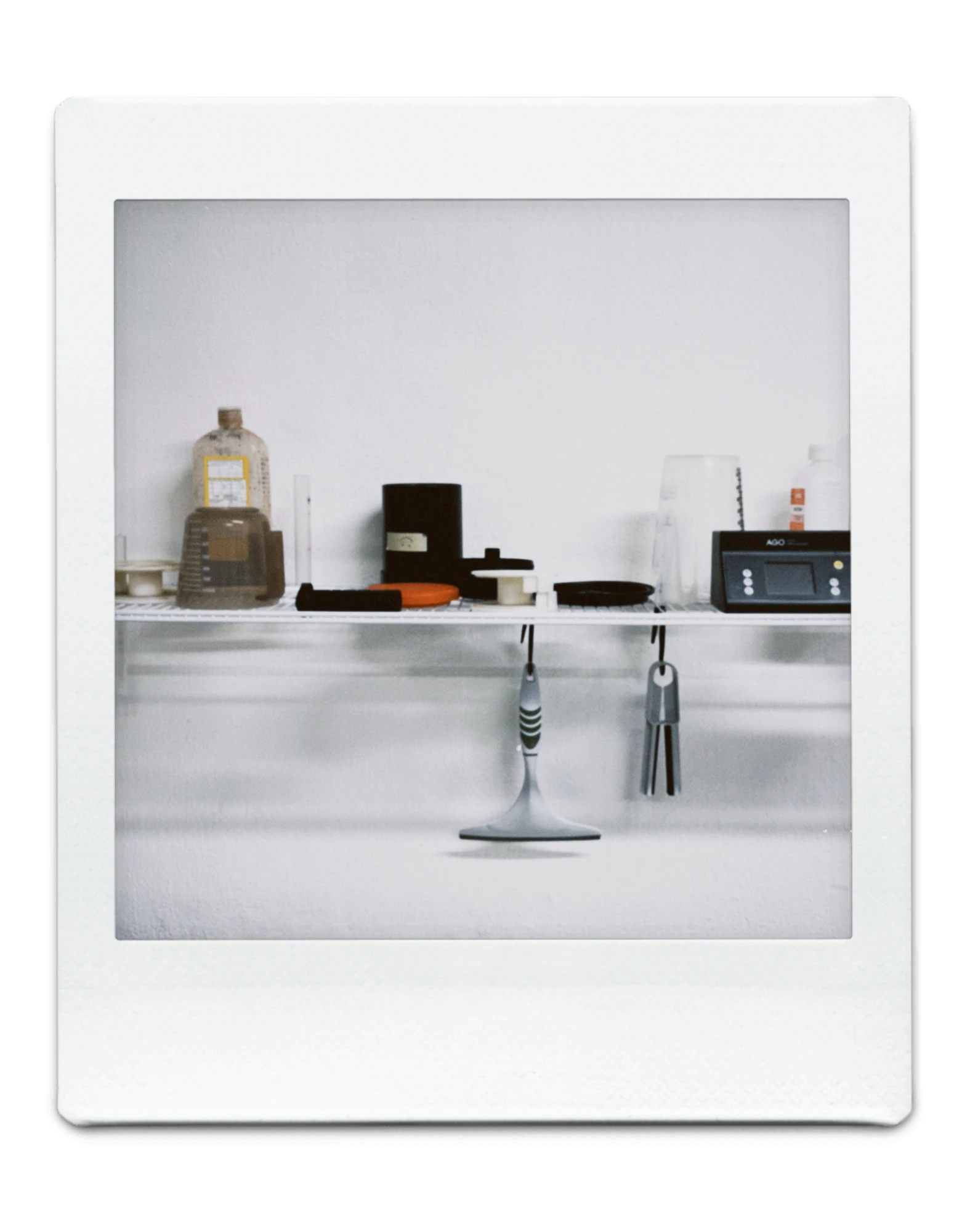 Polaroidfoto laborist: riiul ilmutusvarustusega, selle all rippuvad klambrid
