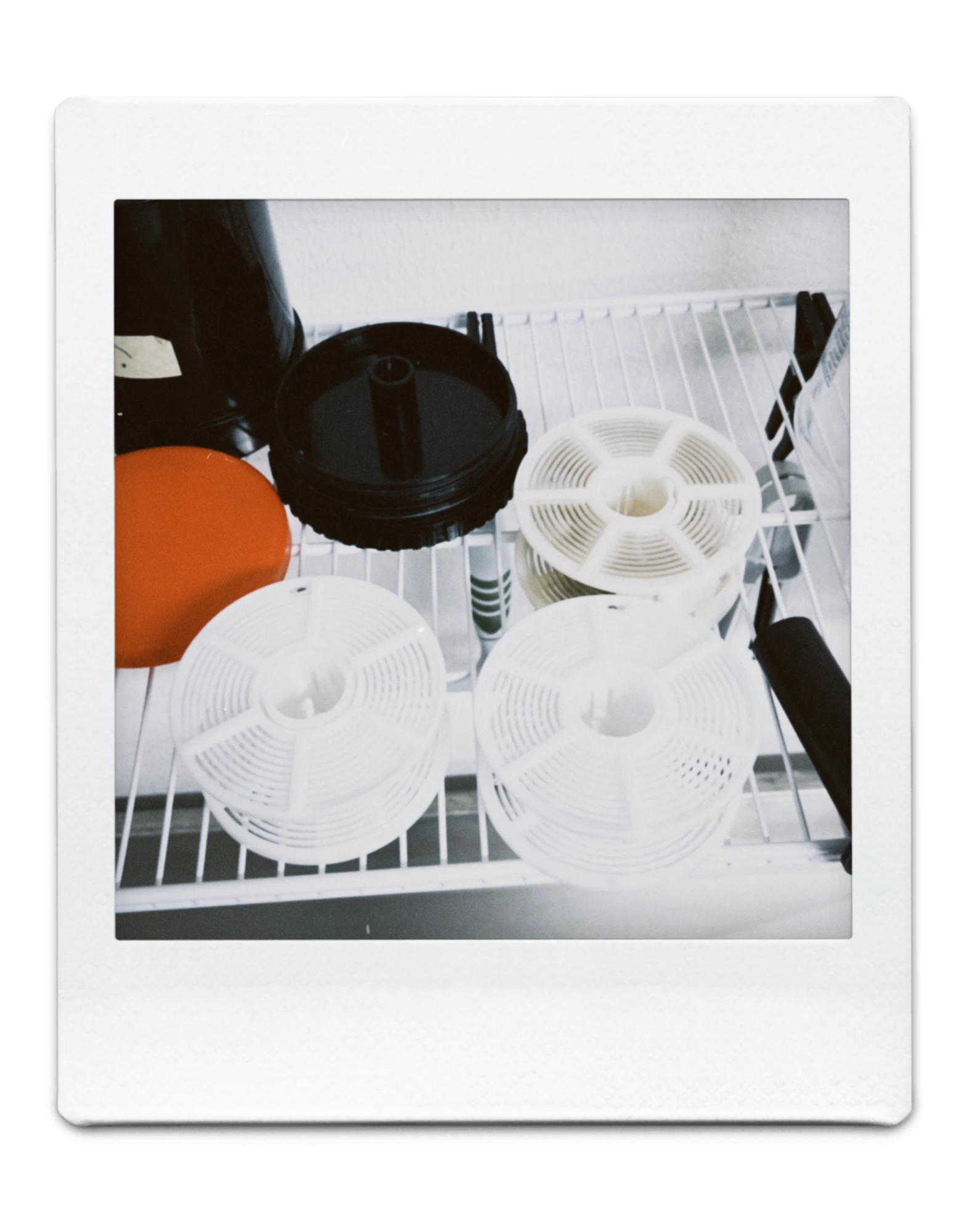 Polaroidfoto laborist: ilmutusspiraalid ja tanki osad traatriiulil